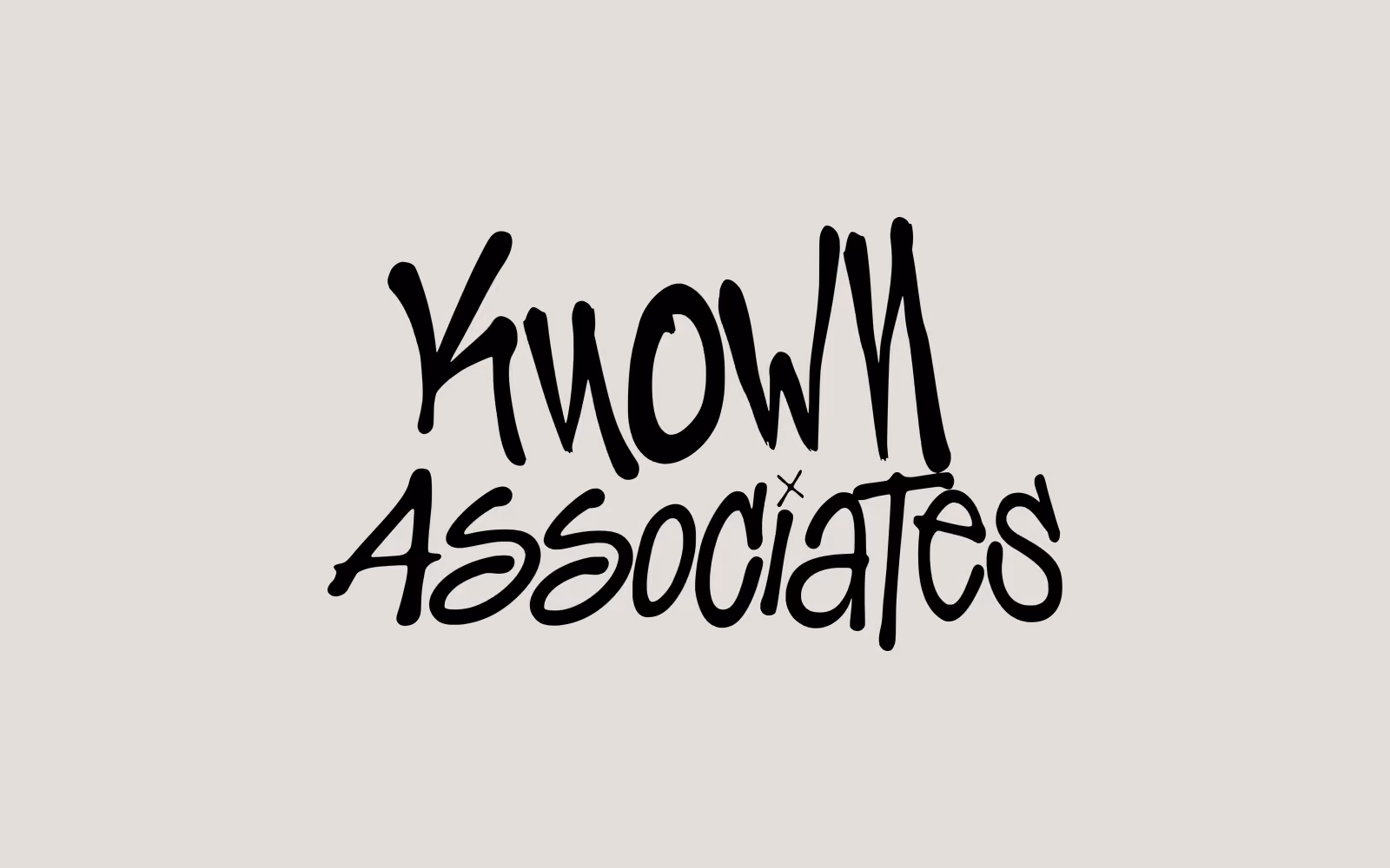 The Known Associates mark in black: the two words hand lettered in a loose marker script, a small cross between them.