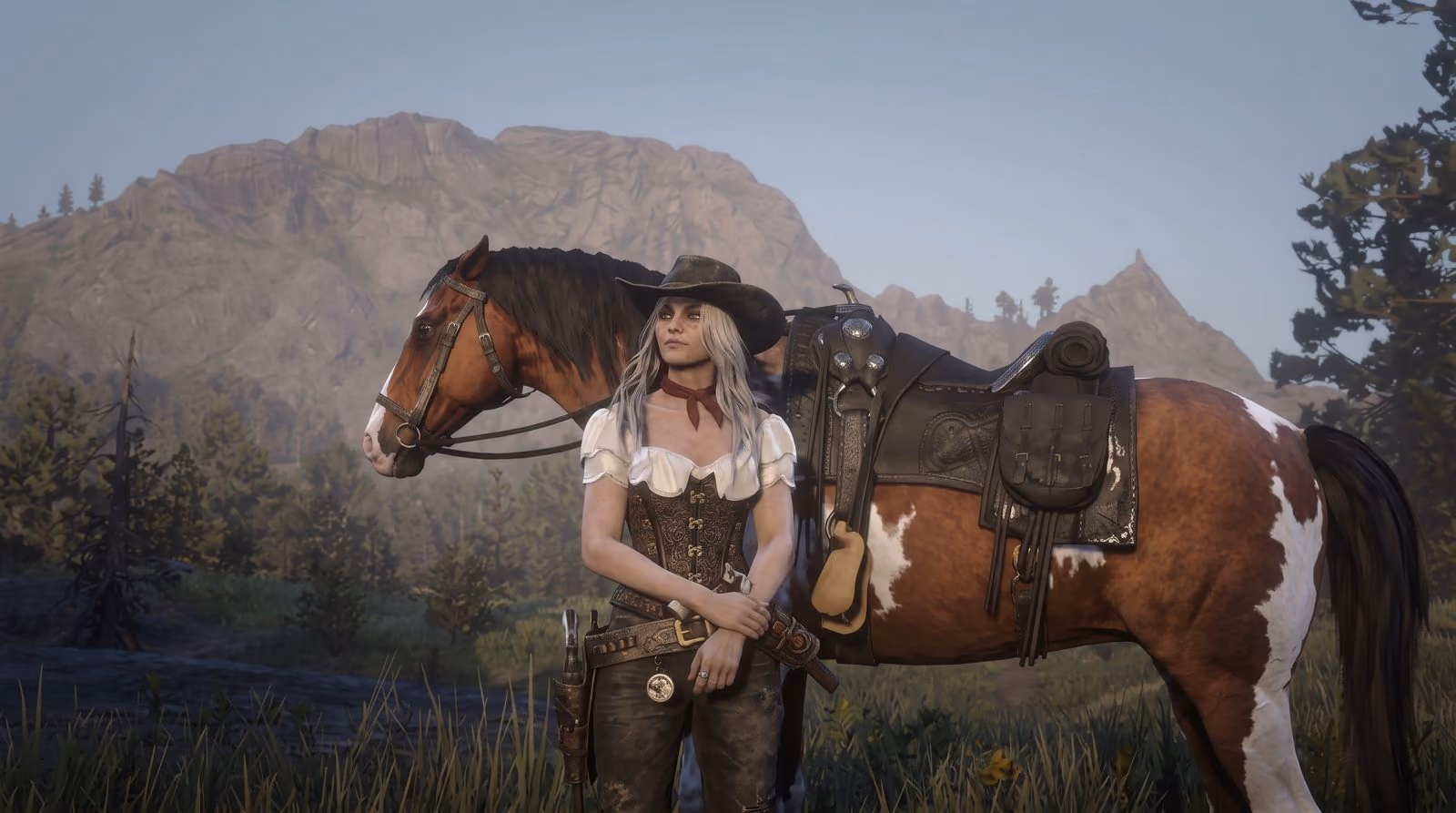 A woman in a corset and boots stands beside a paint horse on a grassy rise, a bare mountain face behind them.