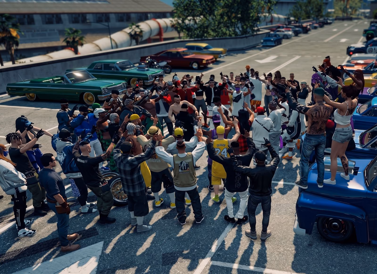Seen from above, a crowd packs a car park between rows of lowriders and tuned cars, hands up, long afternoon shadows across the asphalt.
